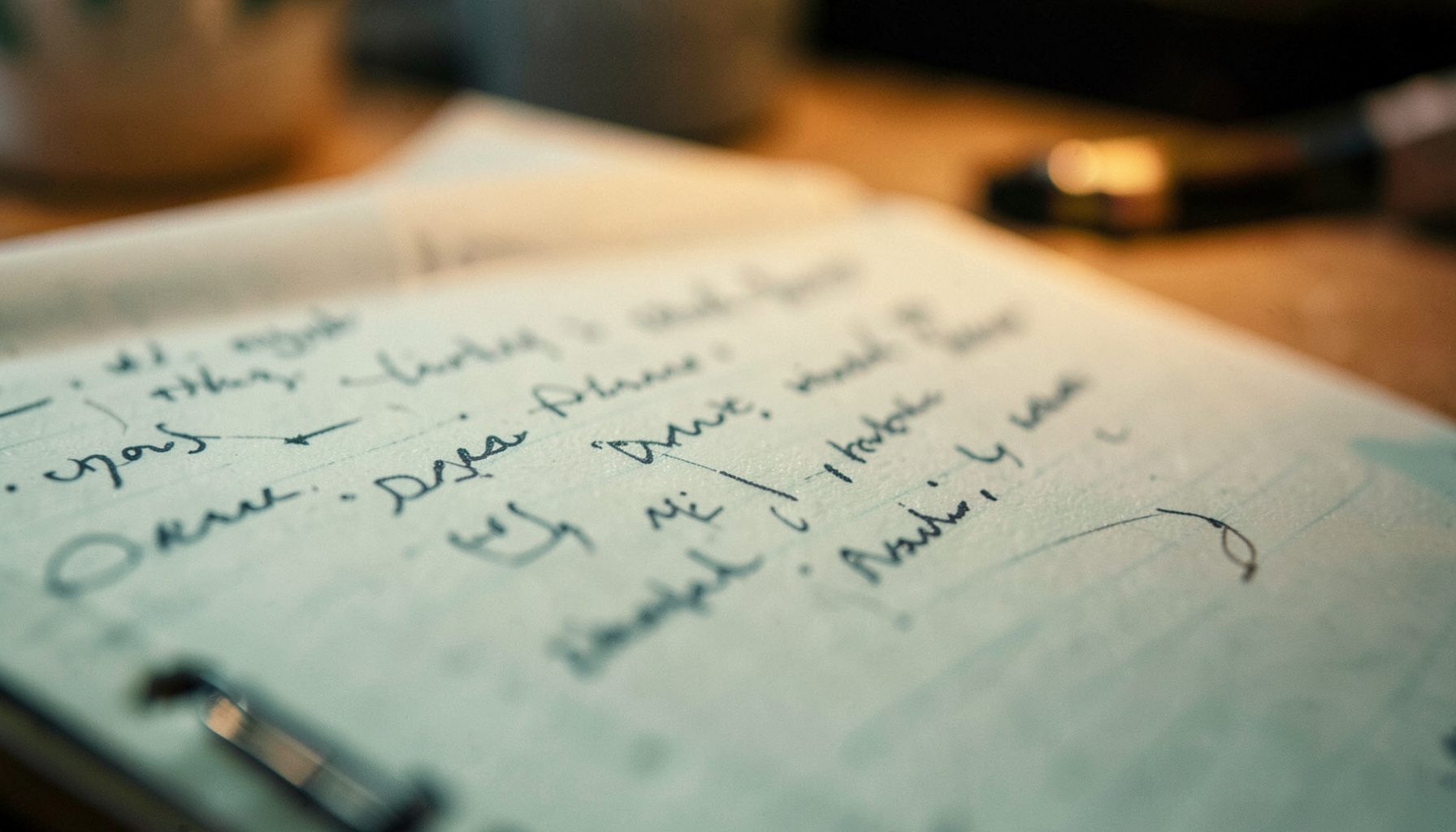 A close-up of a journalist's notepad with handwritten notes, warm desk-lamp lighting