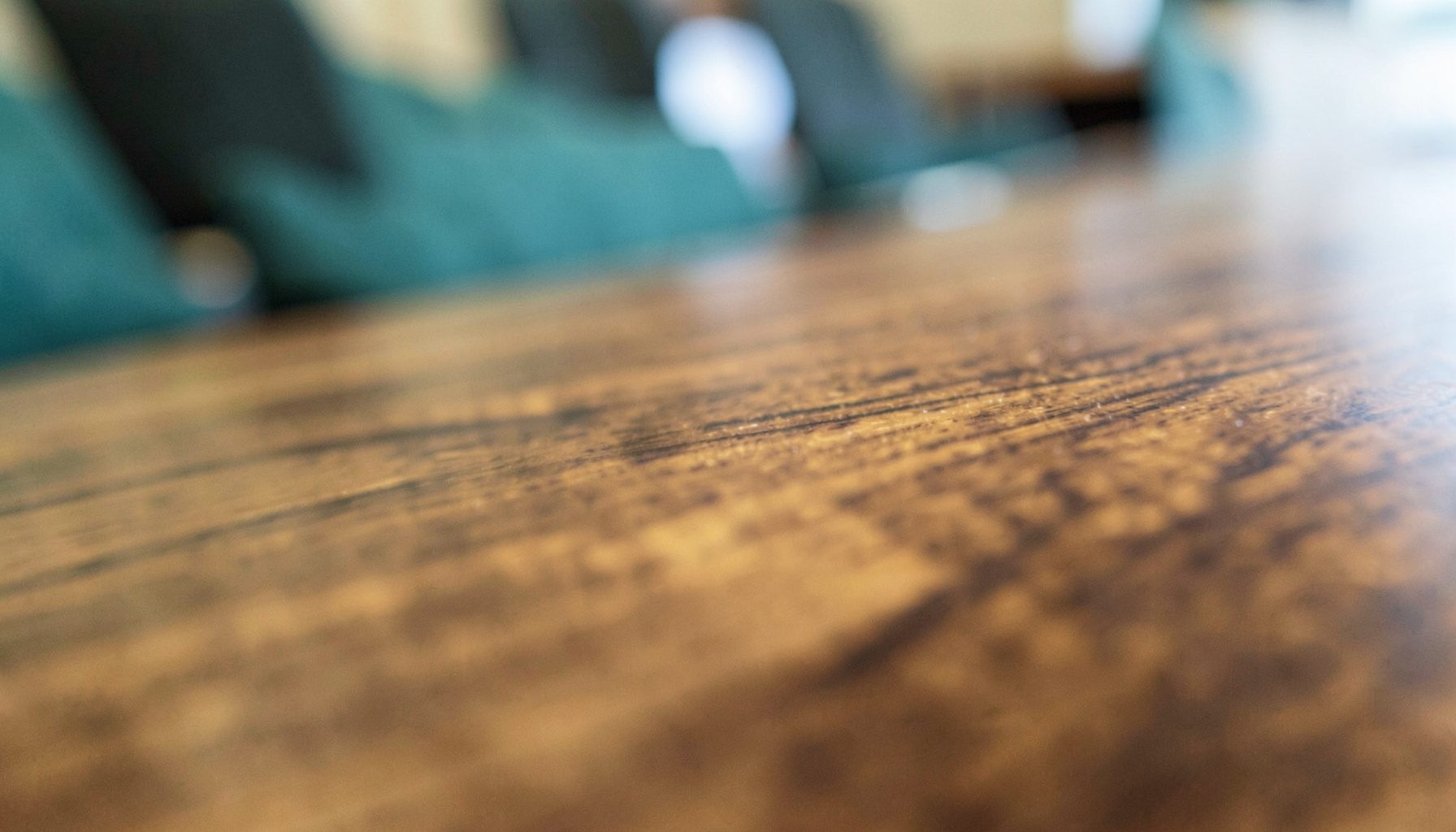 An extreme close-up of polished wood grain, warm brown tones, formal conference setting