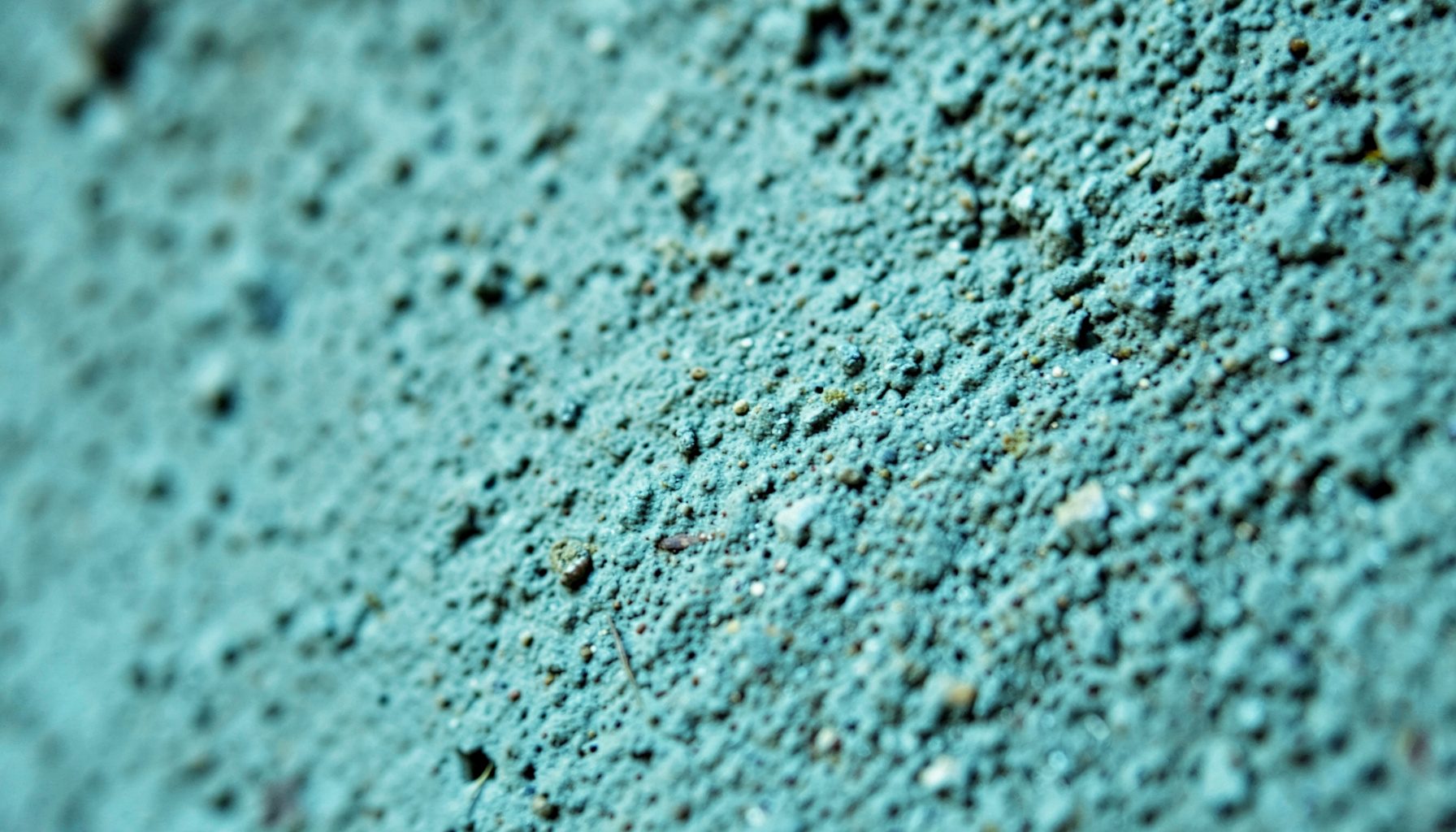 An extreme close-up of a textured concrete wall surface, urban and grounded atmosphere